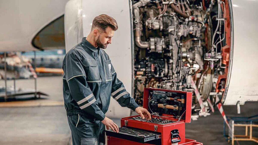 Mechanic performing aircraft maintenance in hangar.